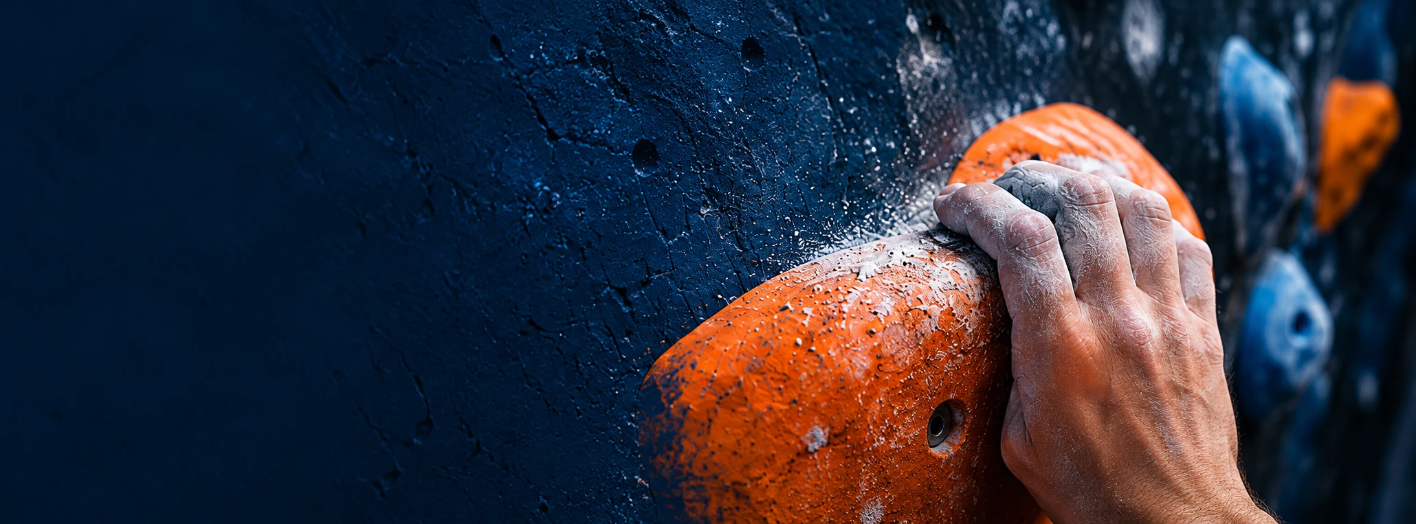 Hånd med kalk på et orange klatregreb